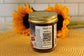A jar of Midnight Chocolate by Sunflour Baking Company with a gold lid, QR code, and shipping info on a yellow mat with sunflowers.
