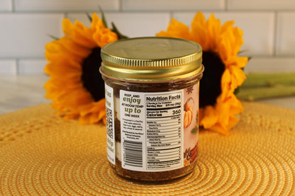 Sunflour Baking Company Pumpkin Spice Cake Jar with gold lid and nutrition facts, set before two sunflowers on a white surface.