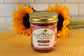 A jar of Sunflour Baking Company Red Velvet sits on a woven mat with sunflowers in the background.