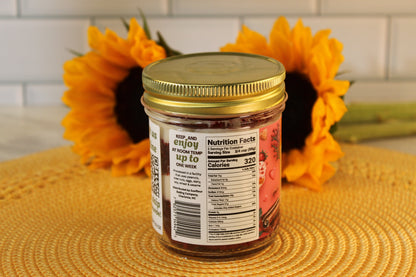 A Sunflour Baking Company Red Velvet Cake Jar with a gold lid sits in front of two sunflowers.