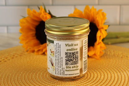 A VGF Blondie Cake Jar from Sunflour Baking Company sits on a yellow mat with sunflowers, gold lid, and QR code label.