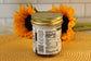 A jar of Sunflour Baking Company VGF Cookies and Cream with a gold lid sits on a mat, sunflowers in the background.