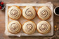 Six fresh-baked Sunflour Baking Company Cinnamon Rolls with white icing, served with coffee and berries—great for gifting.