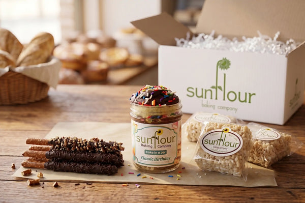 A Birthday Dessert Box from Sunflour Baking Company features a cake jar, chocolate-dipped pretzels, and rice crispy treats.
