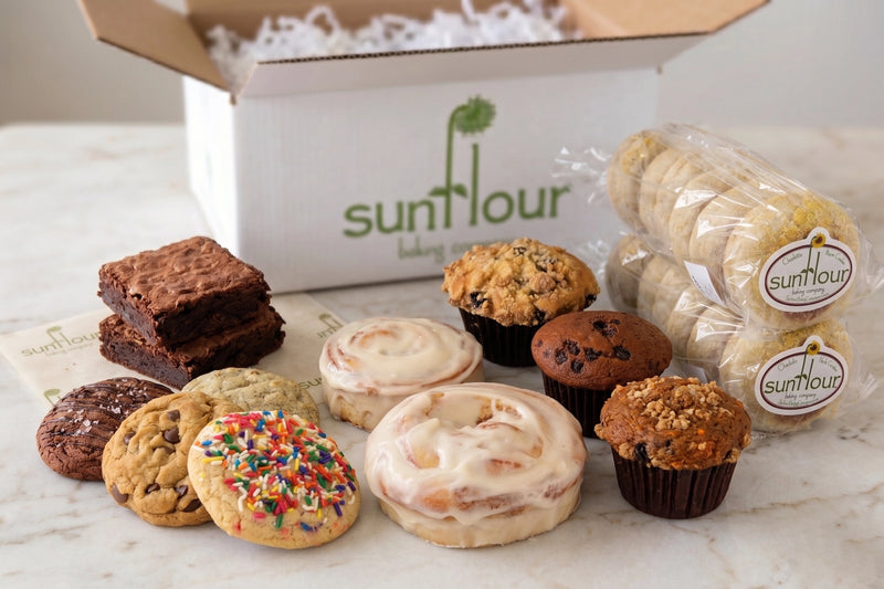 A Sunflour Baking Company Bakery Gift Basket with sourdough English muffins and gourmet cookies displayed on a table.