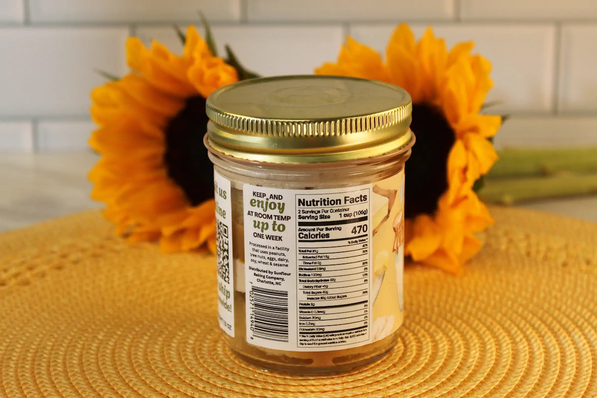 A glass jar with a gold lid by Sunflour Baking Company holds French Toast Cake Jars, perfect for serving and displaying nutrition facts.