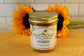 A Sunflour Baking Company French Toast Cake Jar sits on a yellow mat with two sunflowers in the background.