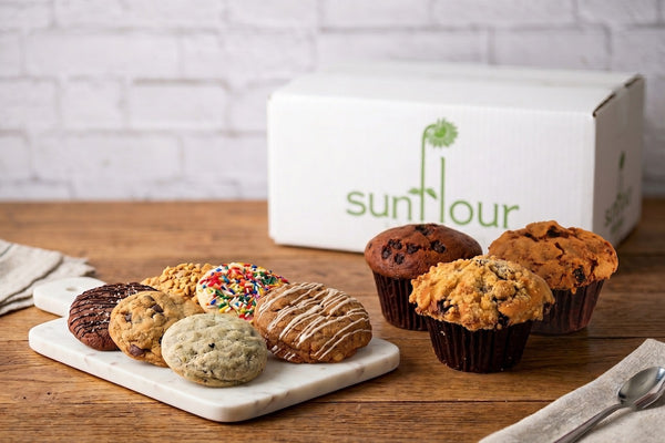 Assorted treats from Sunflour Baking Company’s Sympathy Gift Basket are displayed in front of the gift box on a marble tray.
